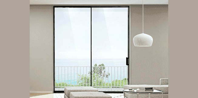 Modern living room with large glass doors overlooking a balcony and a turquoise ocean view.
