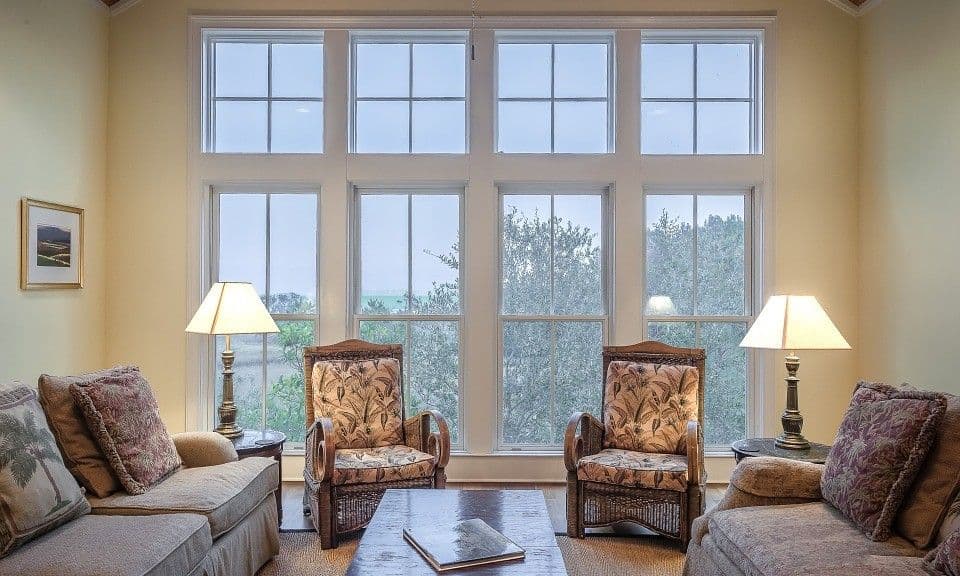 Warm living room with large windows, patterned armchairs, and comfortable sofas.