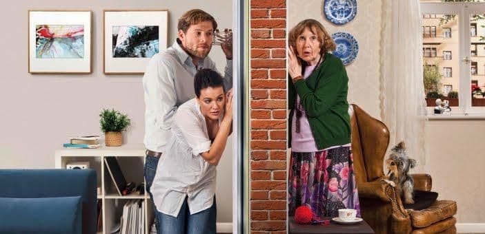 Two couples are secretly peeking around a brick wall with surprised expressions.