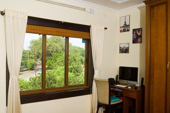A well-lit room with a large window overlooking lush green trees and a bustling road.