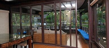 Indoor living area with glass doors opening to a lush garden patio and blue cushions.