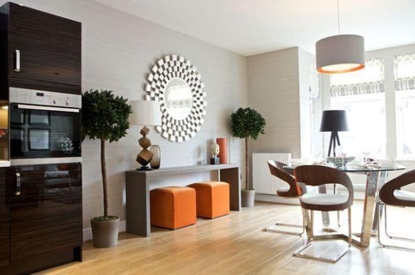 Modern kitchen and dining area with dark cabinets, light wood floor, and decorative mirror.