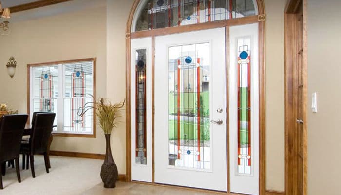 Elegant white front door with decorative stained glass, arched transom, and sidelights in a foyer.