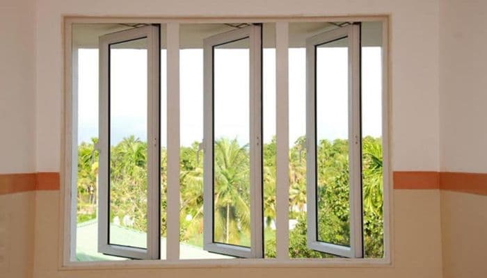 Three open window panes offer a view of lush green trees and a bright sky.