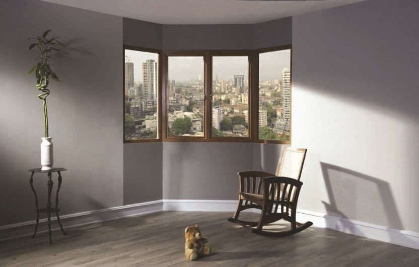 A minimalist room with a bay window overlooking a city, a rocking chair, and a small dog.